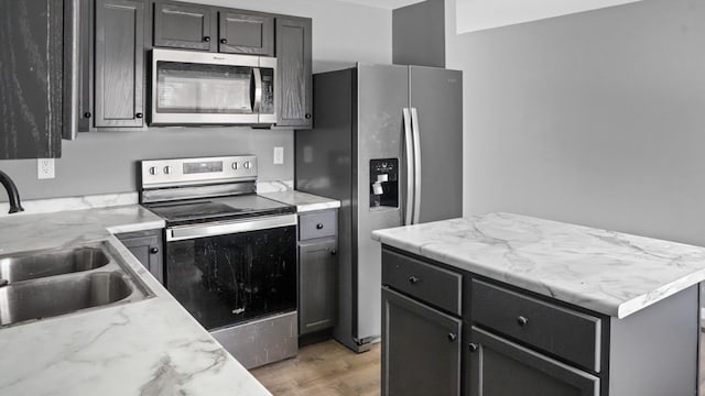 kitchen with sink, light hardwood / wood-style flooring, light stone countertops, and appliances with stainless steel finishes