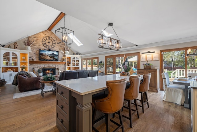 kitchen with decorative light fixtures, lofted ceiling with beams, a kitchen island, a fireplace, and hardwood / wood-style floors