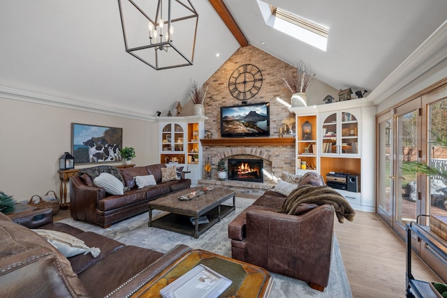 living room featuring beam ceiling, a chandelier, a skylight, a fireplace, and light hardwood / wood-style floors