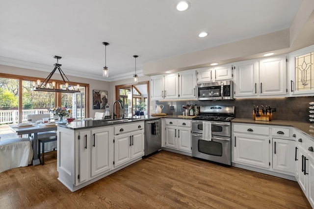 kitchen featuring white cabinetry, appliances with stainless steel finishes, pendant lighting, and kitchen peninsula