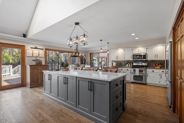 kitchen with appliances with stainless steel finishes, gray cabinetry, hanging light fixtures, tasteful backsplash, and white cabinets