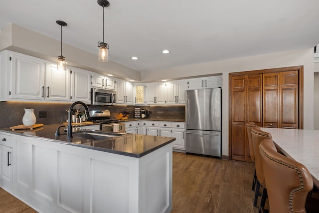 kitchen with dark wood-type flooring, sink, white cabinetry, tasteful backsplash, and appliances with stainless steel finishes