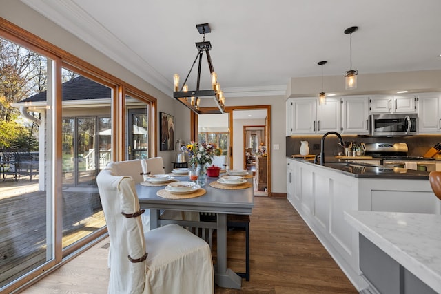 dining area with ornamental molding, wood-type flooring, and sink