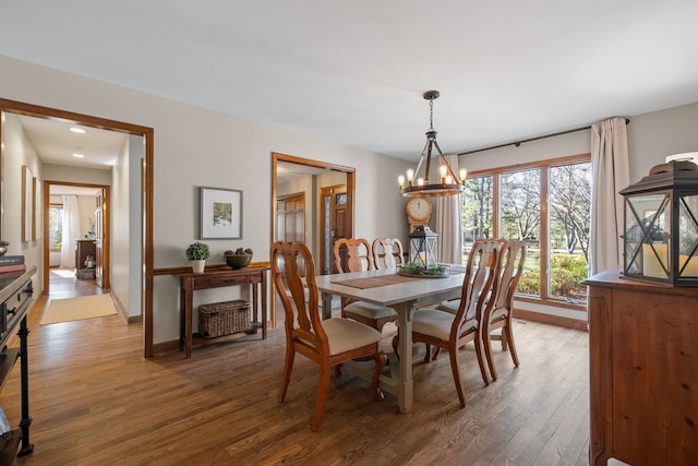 dining space featuring wood-type flooring and a notable chandelier