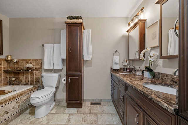 bathroom with vanity, toilet, and tiled tub