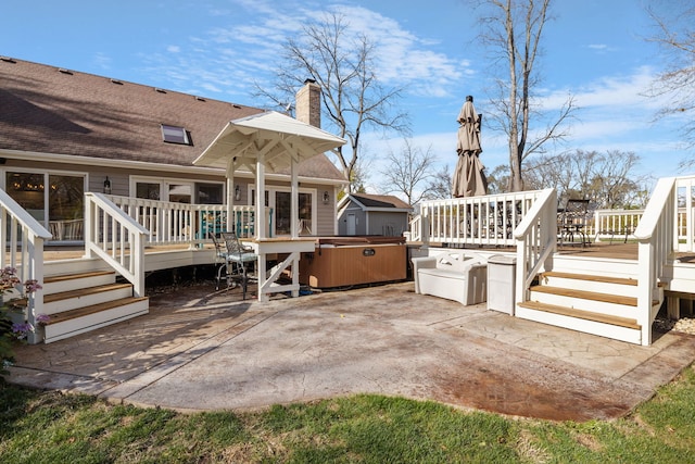 rear view of property featuring a hot tub, a deck, and a patio area