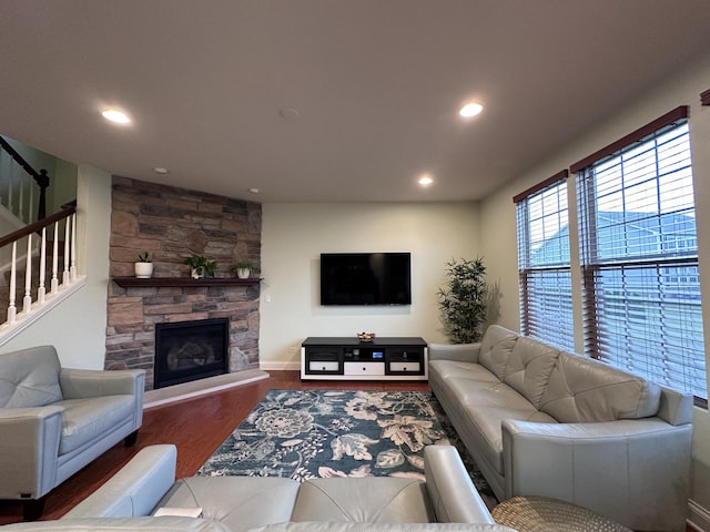 living room with wood-type flooring and a stone fireplace