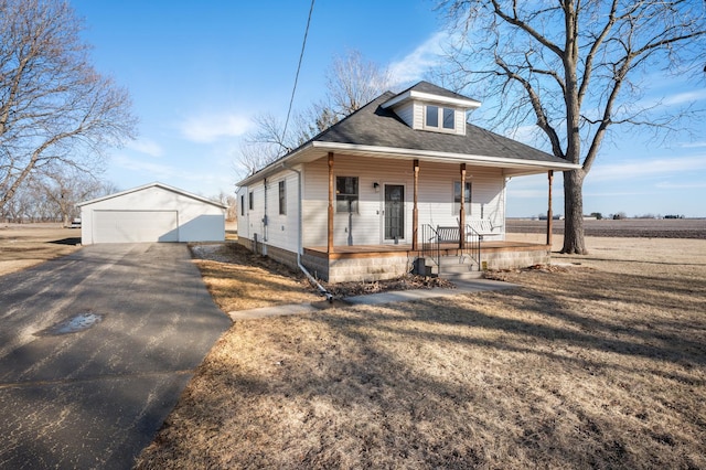 bungalow-style house featuring a garage, covered porch, roof with shingles, and an outbuilding