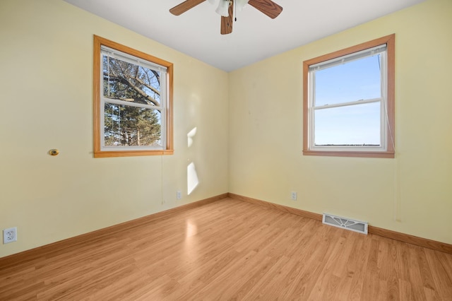 spare room featuring light wood-type flooring, baseboards, visible vents, and a wealth of natural light