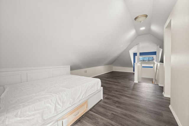 bedroom with baseboards, vaulted ceiling, and dark wood finished floors