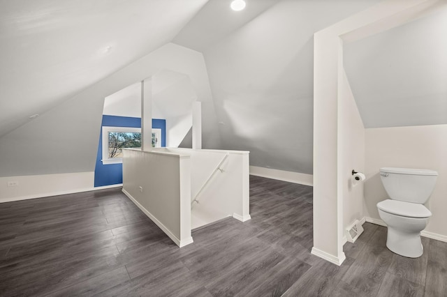 additional living space with baseboards, visible vents, vaulted ceiling, and dark wood finished floors