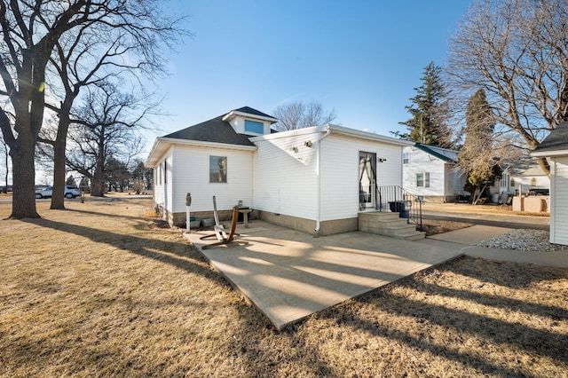 back of house featuring a shingled roof, entry steps, and a yard