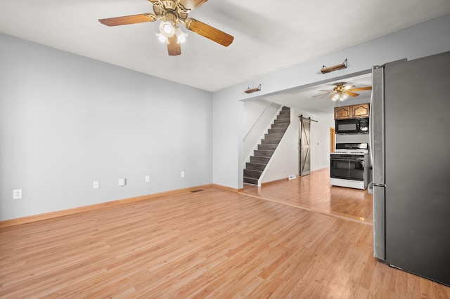 unfurnished living room with light wood-style flooring, stairway, ceiling fan, and baseboards