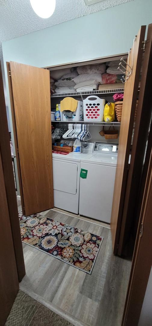 laundry room featuring hardwood / wood-style floors, washer and dryer, and a textured ceiling