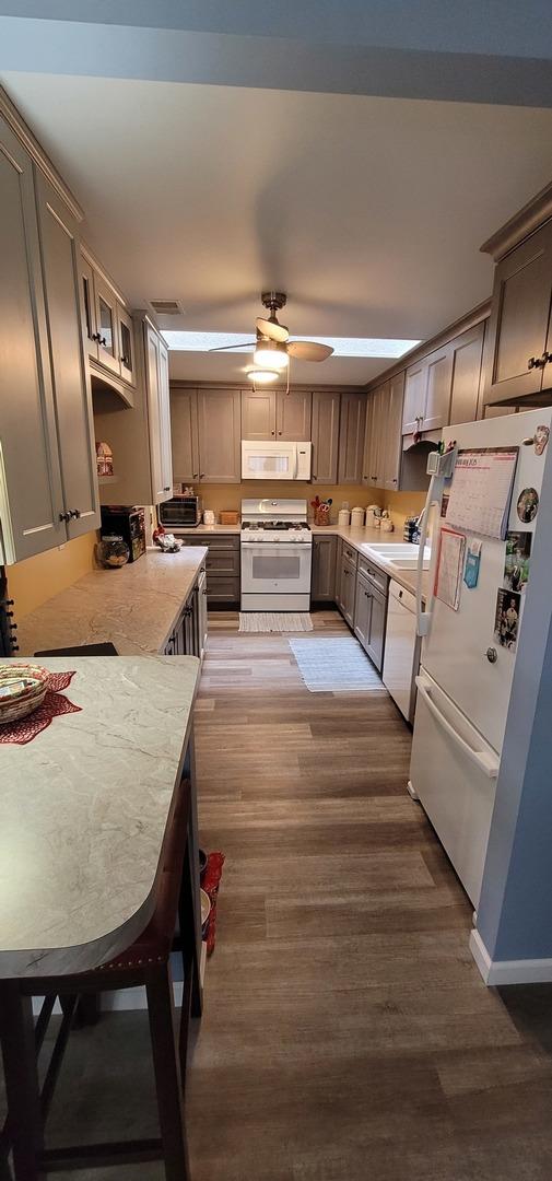 kitchen featuring dark hardwood / wood-style flooring, sink, white appliances, and kitchen peninsula