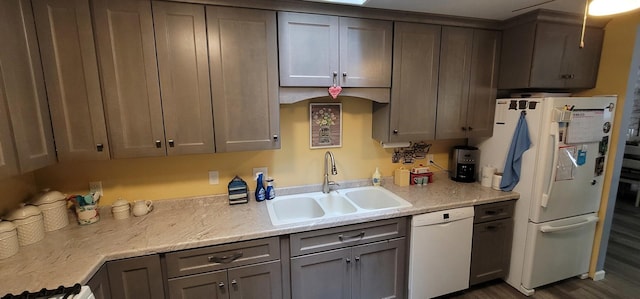 kitchen with sink, light stone counters, white appliances, and dark wood-type flooring