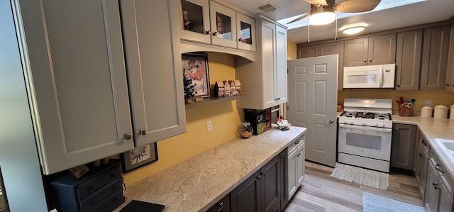 kitchen with gray cabinets, light stone countertops, white appliances, and light hardwood / wood-style flooring