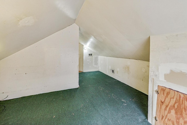 additional living space featuring dark colored carpet and lofted ceiling