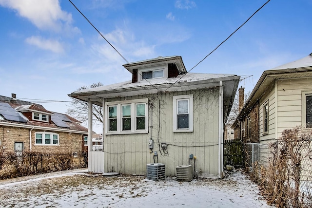 snow covered back of property featuring central AC unit