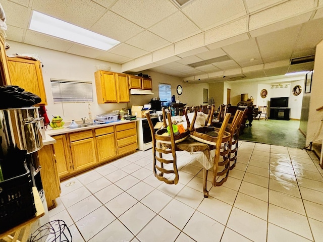 kitchen featuring light tile patterned flooring, stove, sink, and a drop ceiling