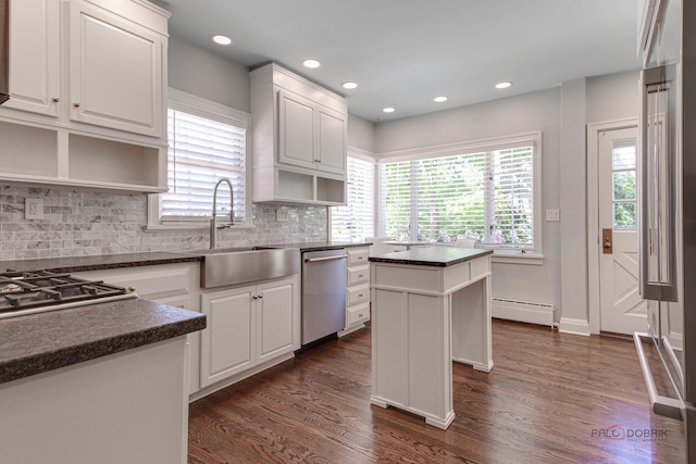 kitchen with sink, stainless steel dishwasher, a baseboard heating unit, a kitchen island, and white cabinets