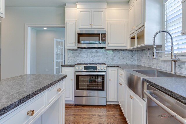 kitchen featuring appliances with stainless steel finishes, dark hardwood / wood-style floors, tasteful backsplash, white cabinetry, and sink