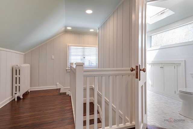 additional living space with dark hardwood / wood-style floors, lofted ceiling with skylight, and radiator