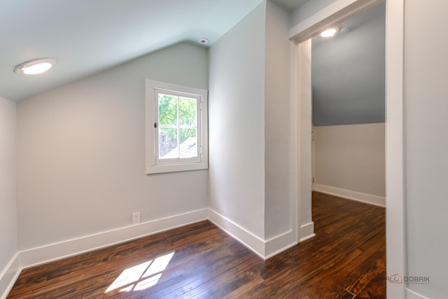 additional living space with dark wood-type flooring and vaulted ceiling