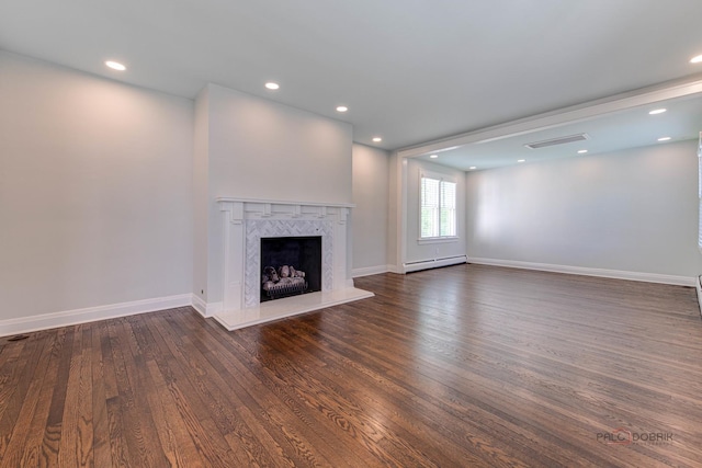 unfurnished living room with a baseboard heating unit, dark wood-type flooring, and a premium fireplace