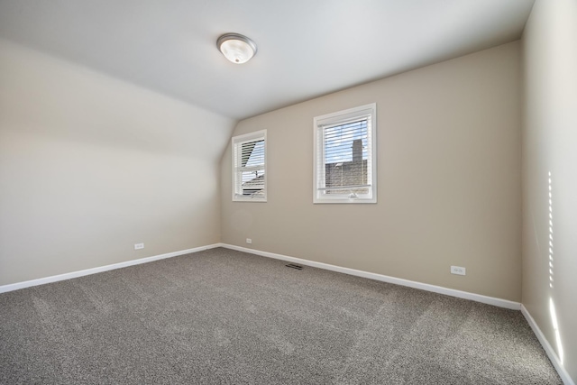 spare room featuring lofted ceiling and carpet flooring