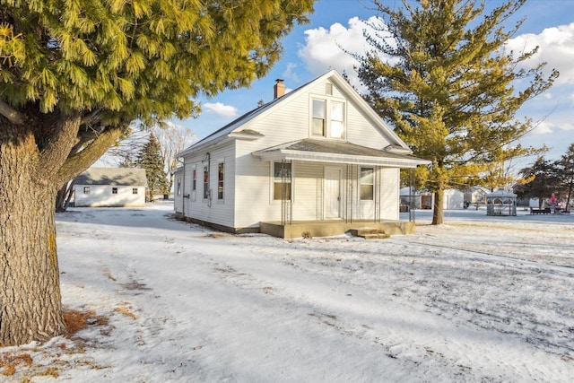 snow covered property with covered porch