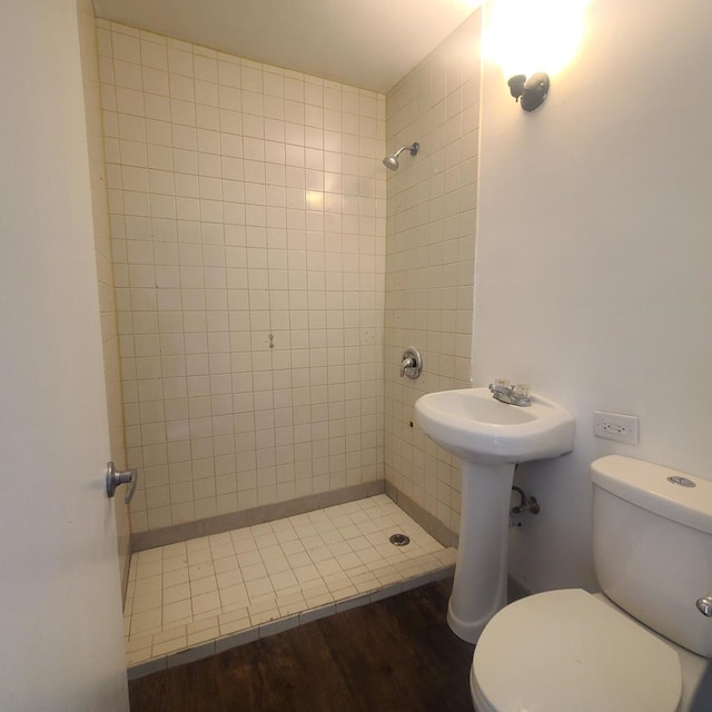 bathroom with tiled shower, toilet, and hardwood / wood-style floors