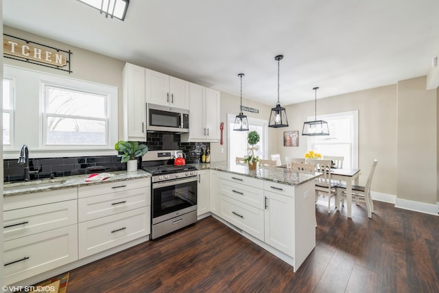 kitchen with white cabinetry, stainless steel appliances, kitchen peninsula, and sink