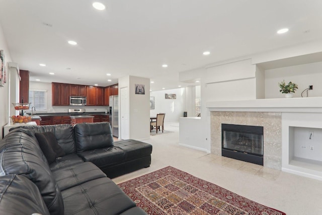 carpeted living room with a tiled fireplace and sink