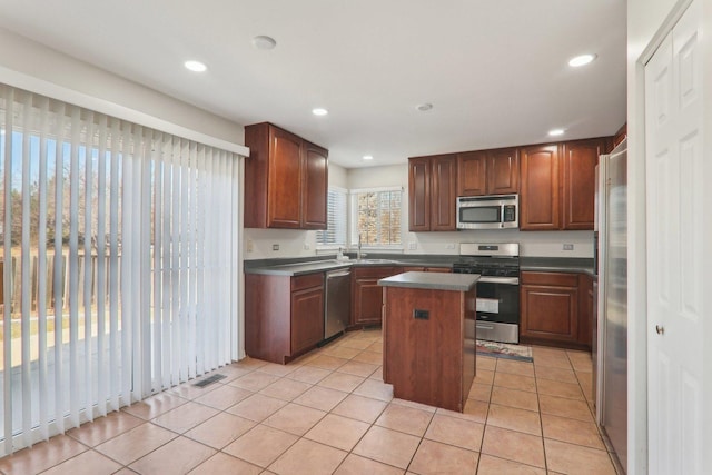 kitchen featuring stainless steel appliances, sink, a center island, and light tile patterned floors