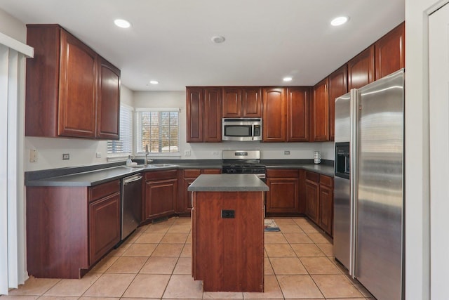 kitchen featuring sink, light tile patterned floors, a kitchen island, and appliances with stainless steel finishes