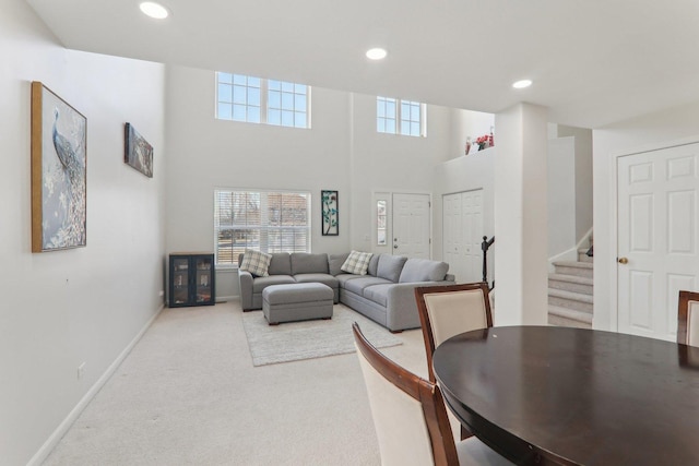 carpeted living room featuring a towering ceiling