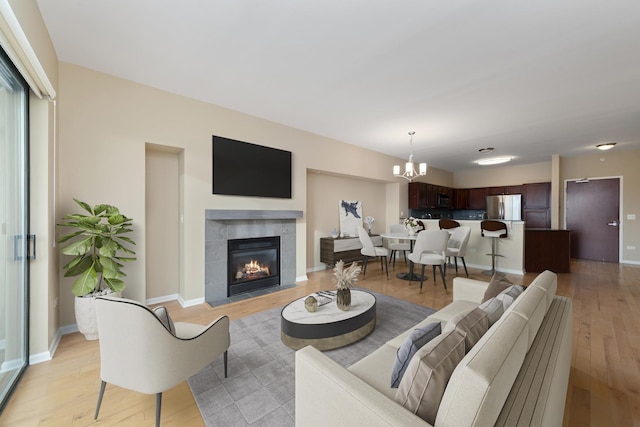 living room featuring a fireplace, a notable chandelier, light hardwood / wood-style flooring, and a wealth of natural light