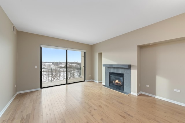 unfurnished living room featuring a tile fireplace and light wood-type flooring