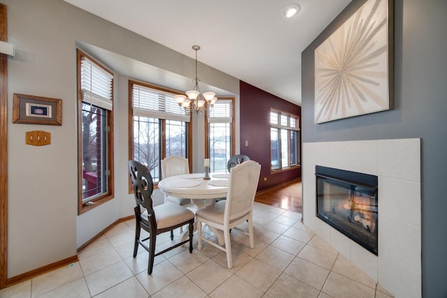 dining space featuring light tile patterned flooring, a healthy amount of sunlight, a fireplace, and a chandelier