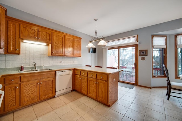 kitchen featuring sink, hanging light fixtures, light tile patterned floors, white dishwasher, and kitchen peninsula