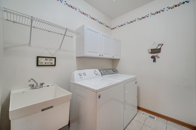 laundry room with cabinets, washing machine and clothes dryer, light tile patterned flooring, and sink