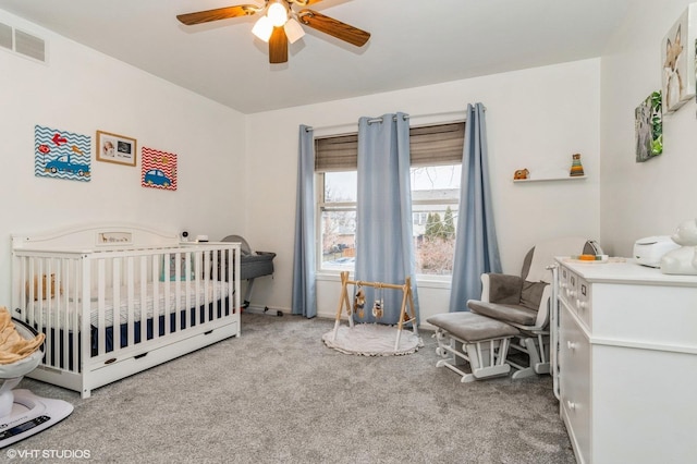 bedroom with a nursery area, ceiling fan, and carpet floors