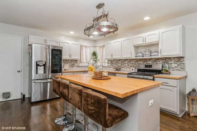 kitchen featuring wood counters, a breakfast bar, a center island, appliances with stainless steel finishes, and white cabinets