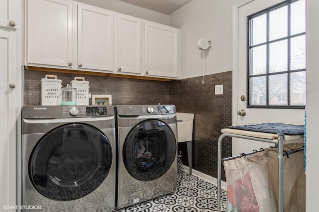 laundry room featuring cabinets, plenty of natural light, tile patterned flooring, and washing machine and clothes dryer