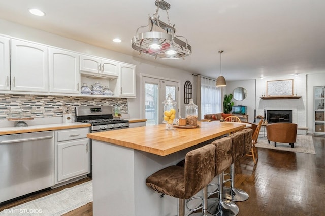 kitchen with stainless steel appliances, butcher block counters, a breakfast bar area, and white cabinets