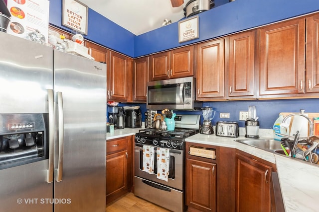 kitchen featuring stainless steel appliances, sink, light stone counters, and light hardwood / wood-style floors