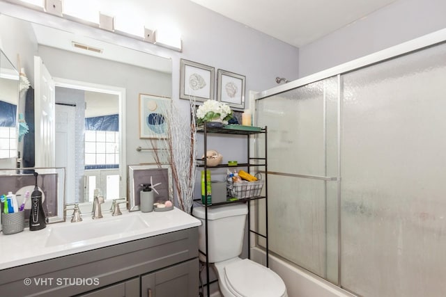 full bathroom with vanity, shower / bath combination with glass door, and toilet