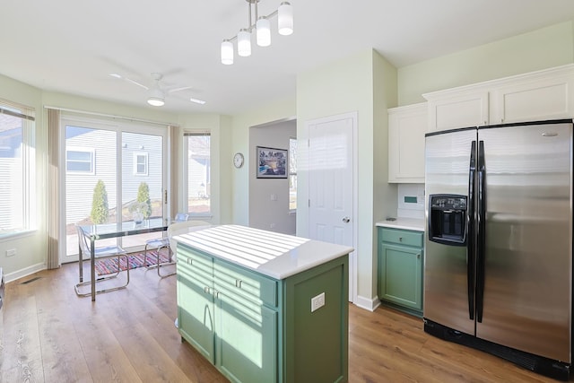 kitchen with decorative light fixtures, stainless steel fridge, green cabinets, a kitchen island, and white cabinets