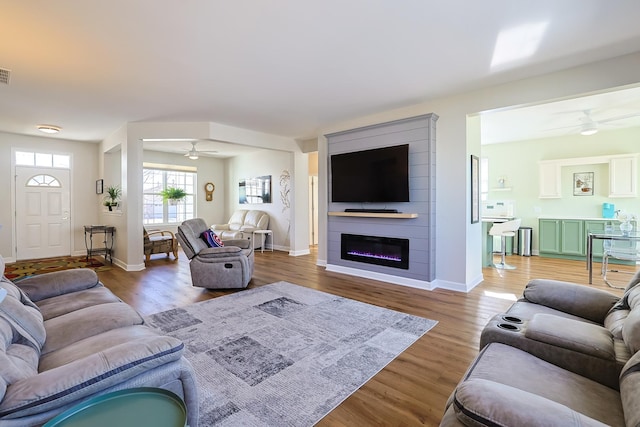 living room with hardwood / wood-style floors, a large fireplace, and ceiling fan